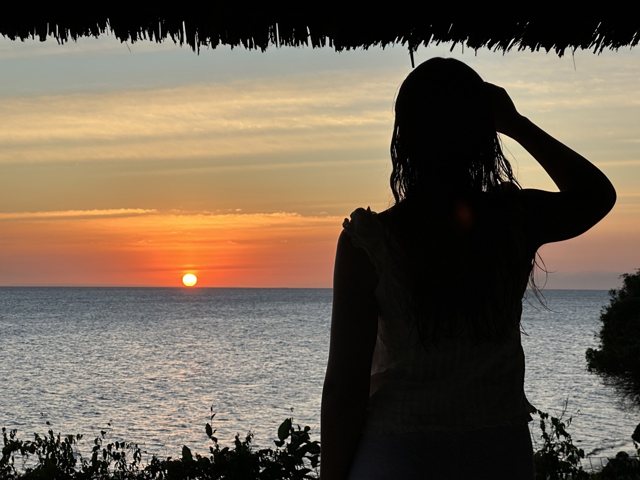 Silhouette of a woman watching sunset over the ocean at Villa Heidi Zanzibar